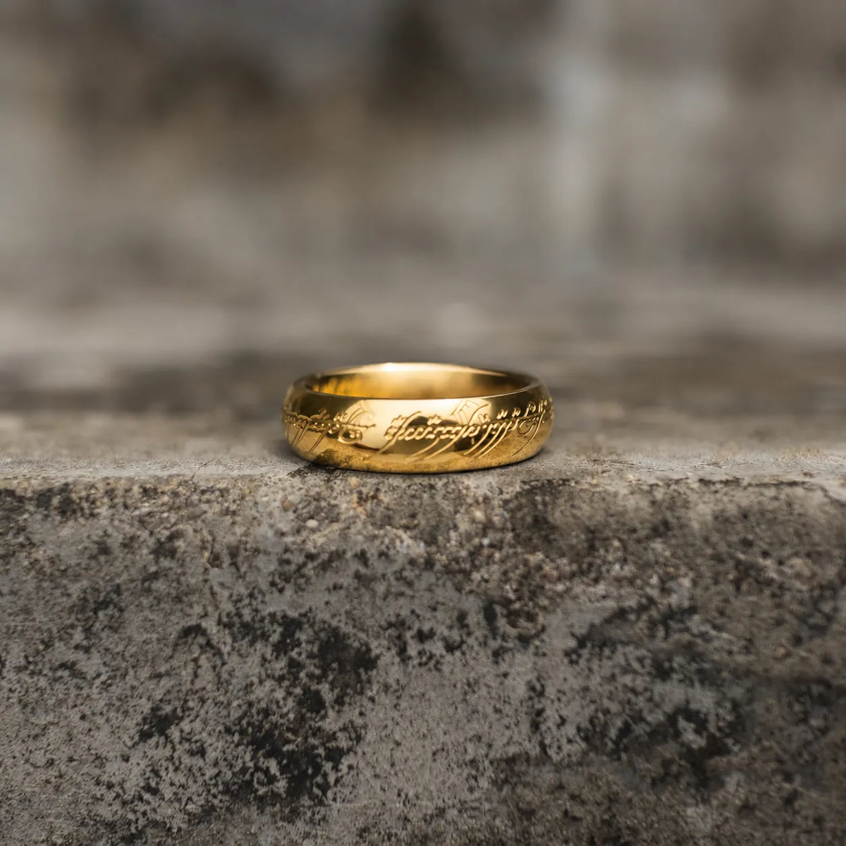Highly polished gold-tone band ring with engraved script shown upright from the side Main image