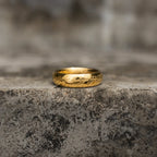 Highly polished gold-tone band ring with engraved script shown upright from the side