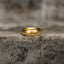 Highly polished gold-tone band ring with engraved script shown upright from the side
