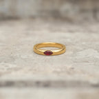 Gold-tone band ring with a red marquise stone shown from the front
