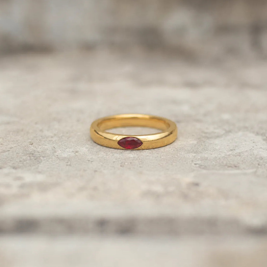 Gold-tone band ring with a red marquise stone shown from the front
