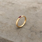 Gold-tone band ring with a red marquise stone shown upright from the side