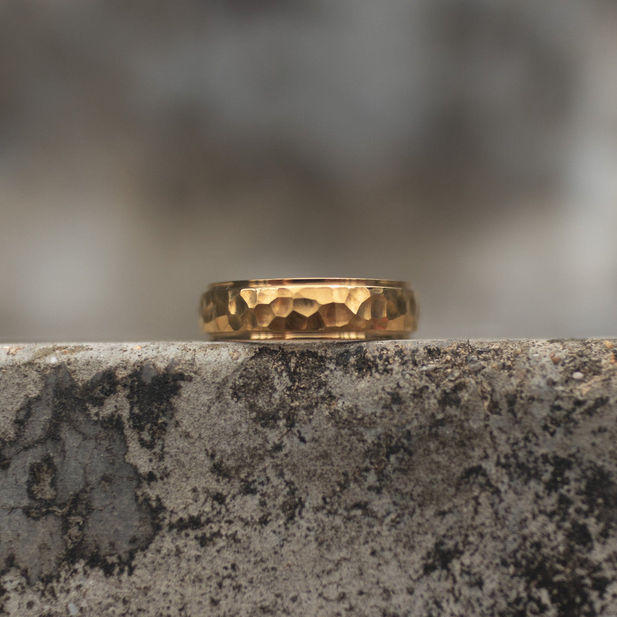 Gold-tone band ring with a polished faceted center and smooth raised edges, front view Main image