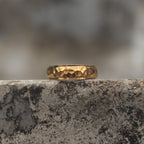 Gold-tone band ring with a polished faceted center and smooth raised edges, front view