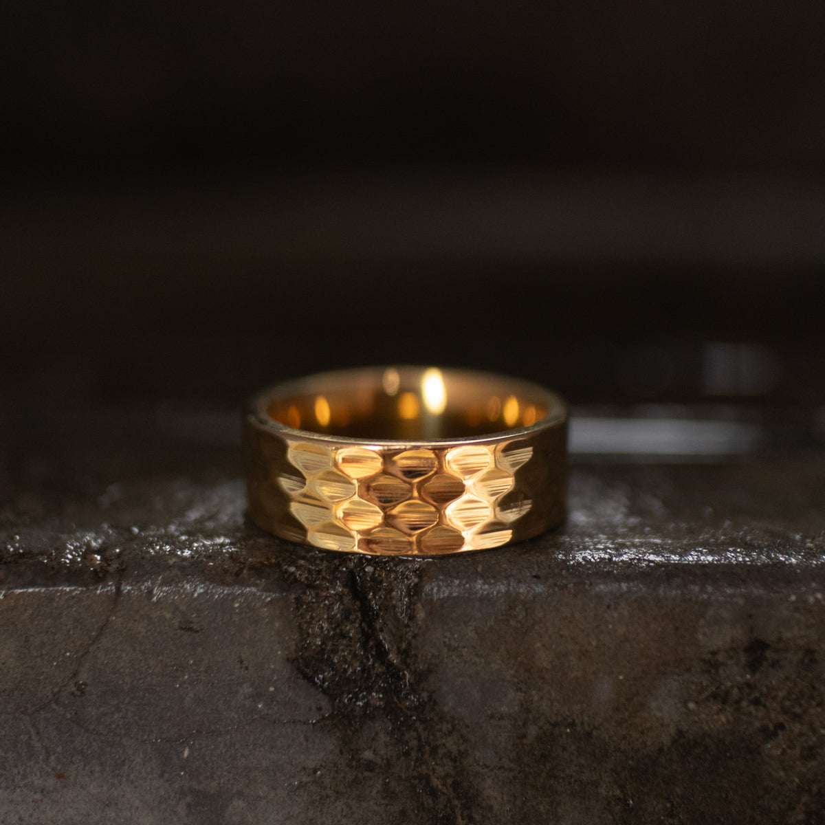 Gold-tone wide band ring with a repeating geometric faceted pattern