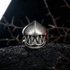 Front view of the gothic monster teeth ring with dramatic fang design placed on cracked dark rock in shadowy gothic setting