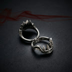 Gothic beast fang ring shown open on its hinge, revealing sharp monster teeth details against dark background with red smoke