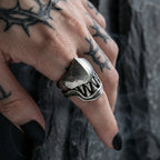 Gothic beast fang ring worn on tattooed hand with black nails, highlighting the hinged monster teeth design in dark gothic atmosphere