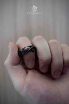 Gothic black thorn ring worn on a clenched fist, sharp branch-like spikes circling the band in a matte dark metal finish