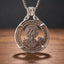 grim reaper hobo coin pendant necklace — robed reaper figure with scythe hand-cut on 1921 Morgan Dollar coin face, E pluribus unum inscription, crescent moon and sun detail, four-prong open frame, skull bail, antique silver tone, dark wood surface