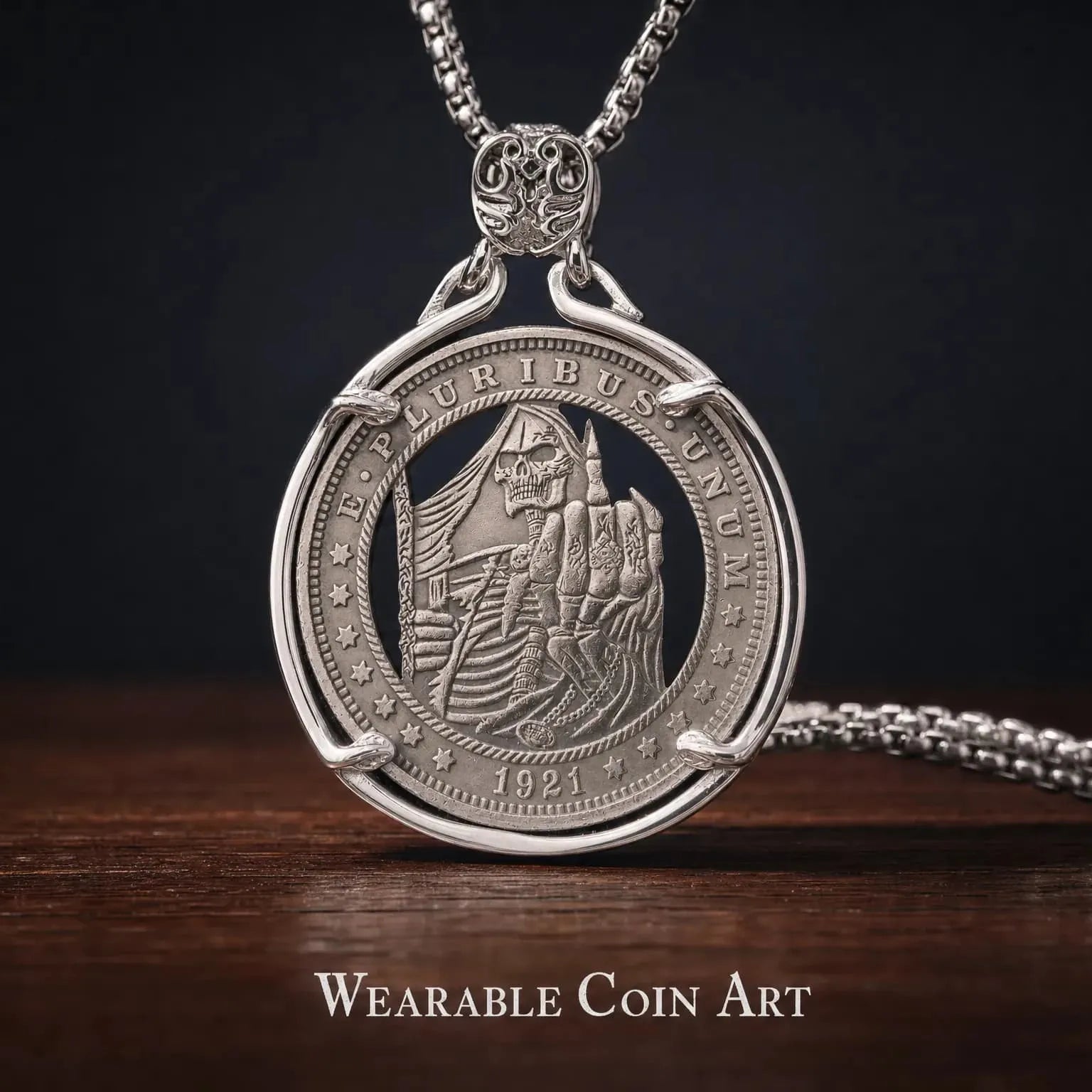 grim reaper coin pendant — skeleton figure holding scythe and raising middle finger, engraved on replica coin in circular silver frame, 1921 inscription, wooden surface