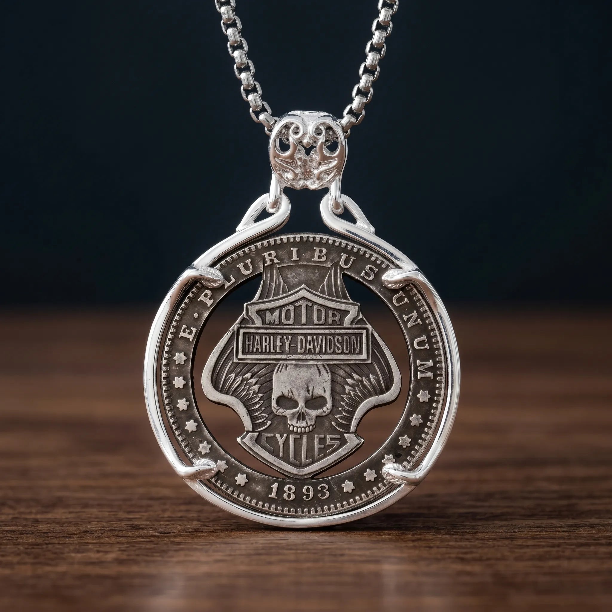 biker skull coin pendant necklace — shield badge with skull and wings hand-cut on coin face, E pluribus unum 1893 inscription, four-prong open frame, skull bail, antique silver tone, dark wood surface Main image