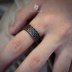Extreme close-up of a hexagonal honeycomb ring showing the raised grid pattern in dark oxidized metal, clean geometric texture across the wide band surface