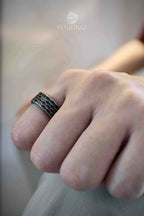 Black oxidized honeycomb pattern band ring worn on a bent finger, hexagonal grid covering the full band width with deep dark fill between cells