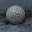 Close-up of a coin engraved with a Spanish conquistador in a morion helmet and armor, ornate scrollwork background, Medio Balboa inscription across the top, on dark stone