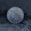 Close-up of a coin engraved with Medusa in profile, serpent hair coiling outward, Liberty above, In God We Trust below, dated 1923, on dark stone