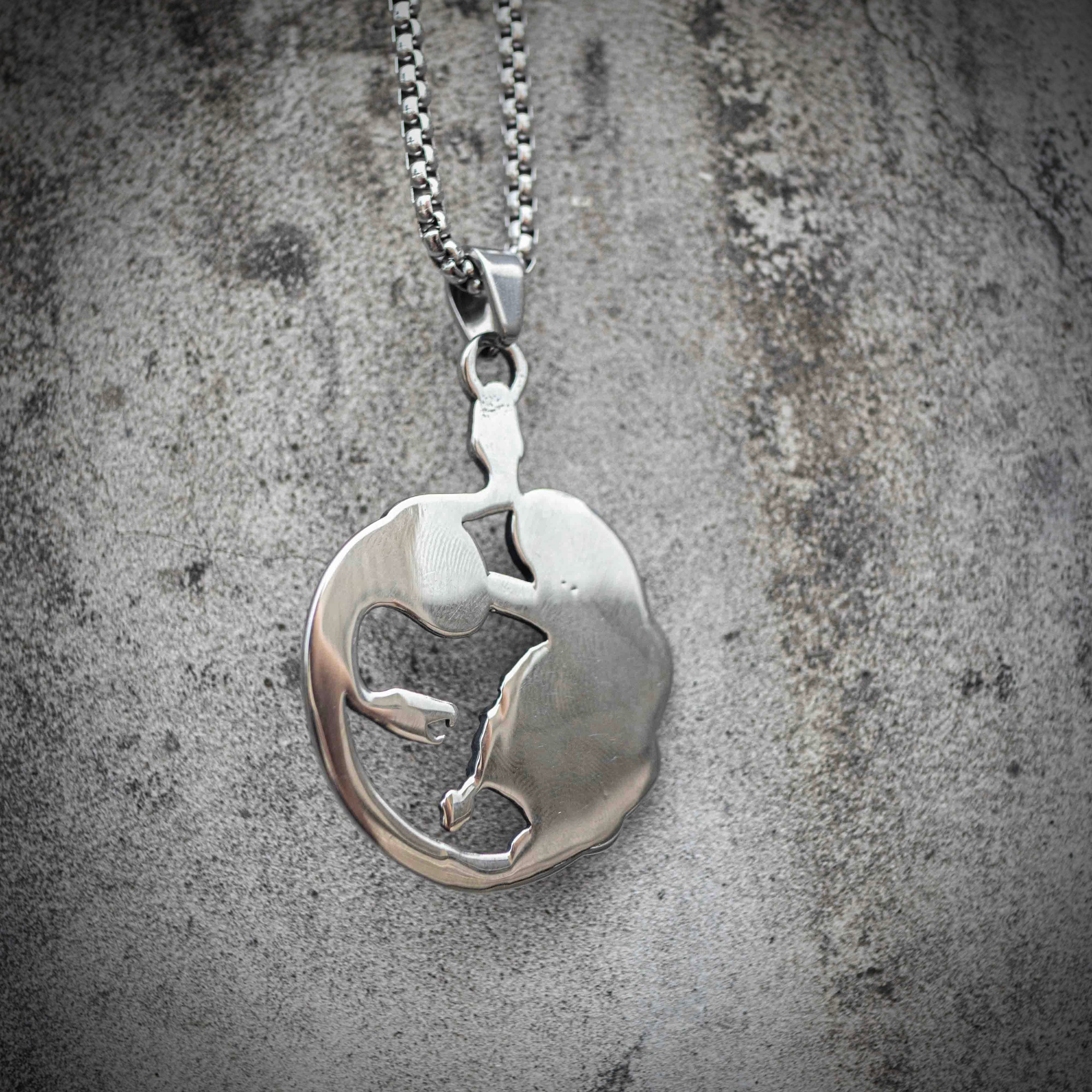 Back of Medusa pendant showing smooth oval silver surface with subtle raised relief — clean reverse finish, box chain clasp visible