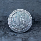 Close-up of a coin engraved with Medusa standing with coiled serpent tail among crumbling stone columns, E Pluribus Unum border, dated 1902