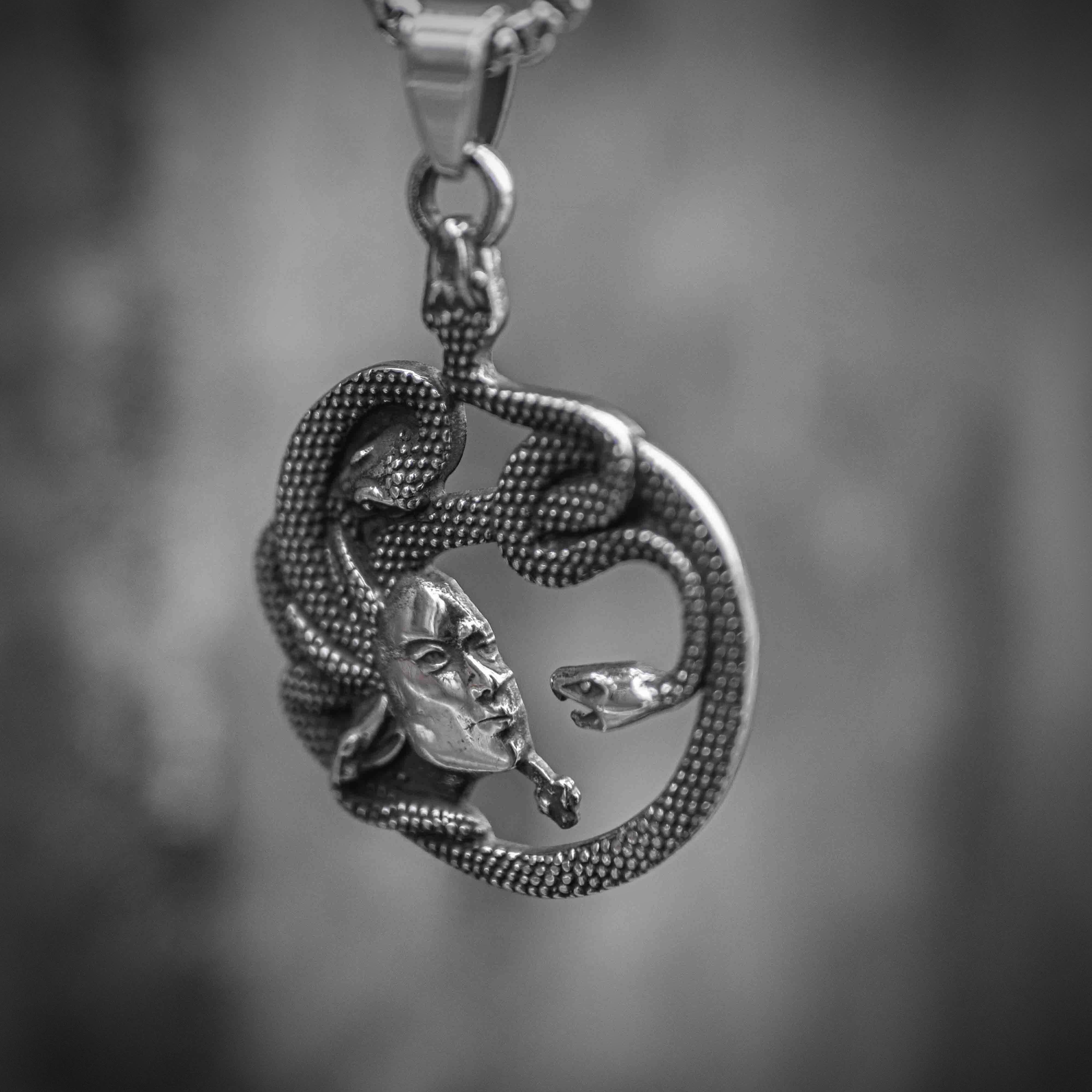 Medusa pendant front — serpent-wreathed face within circular openwork frame, oxidized silver, suspended on box chain Main image