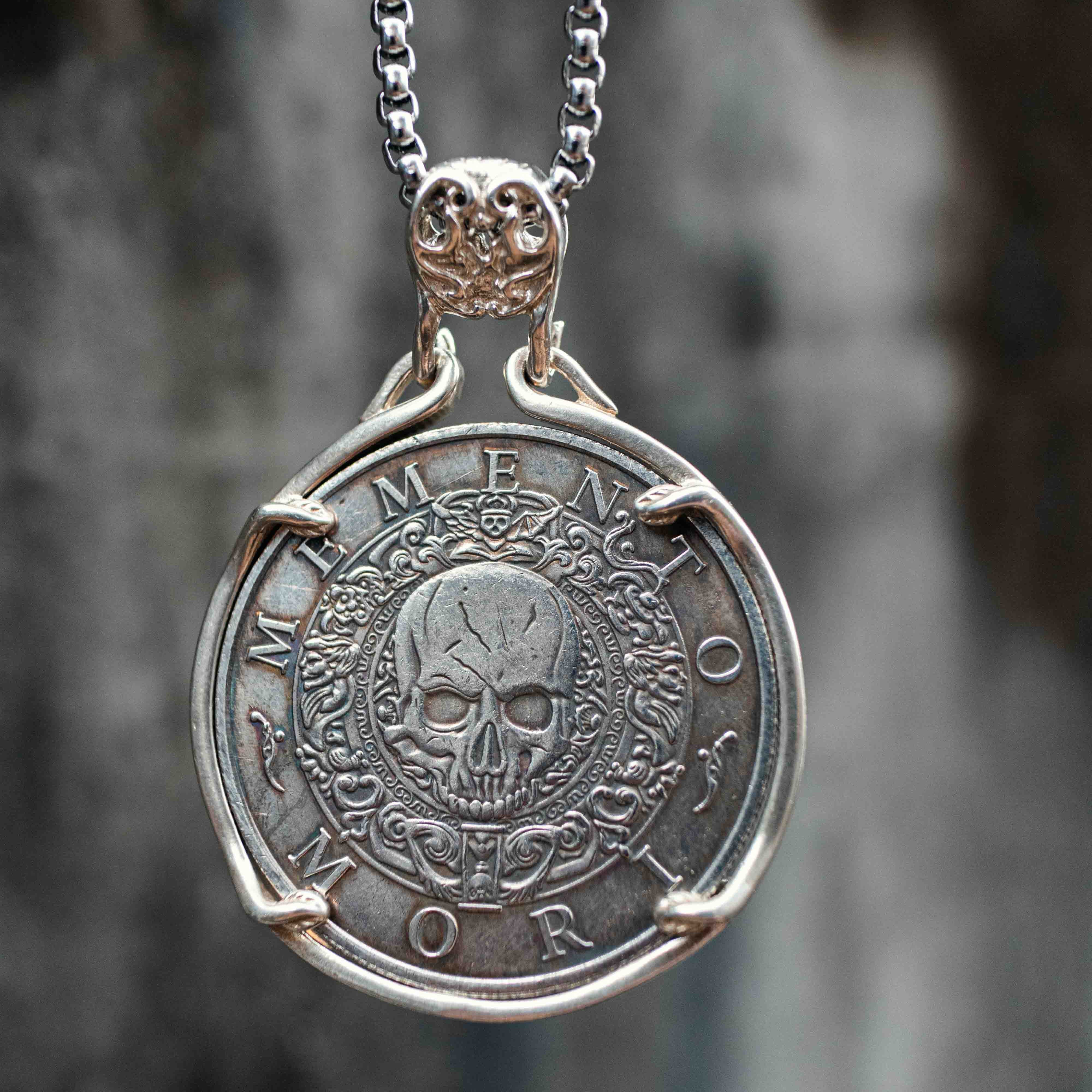 Silver coin pendant necklace engraved with Memento Mori skull motif, suspended from an ornate chain Main image