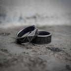 Two minimalist black rings stacked together — geometric diamond faceted band and plain sandblasted band in oxidized stainless steel, dark aesthetic ring stack by Veilhinge