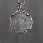 Coin pendant engraved with a moon goddess figure holding a full moon, surrounded by crescent moon phases and cloud border, set in a four-prong bezel on a decorative chain