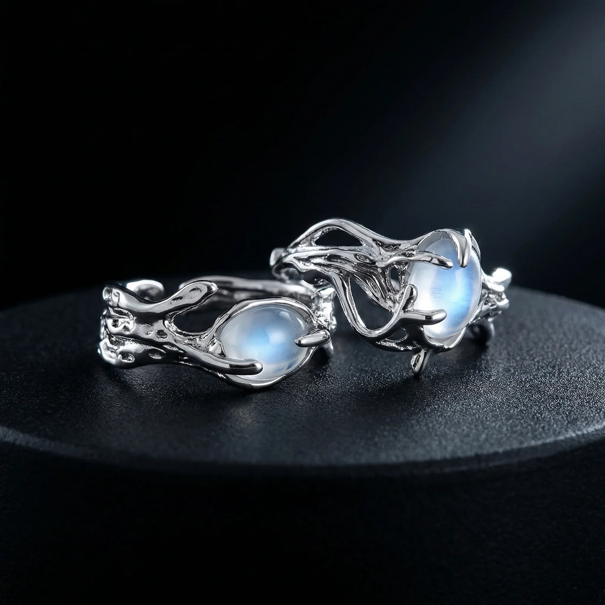 Pair of adjustable moonstone tentacle rings in silver with glowing moonstone cabochons on dark moody background Imagen principal del producto