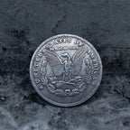Morgan Dollar reverse showing the American eagle, In God We Trust and United States of America inscriptions, One Dollar denomination on dark stone