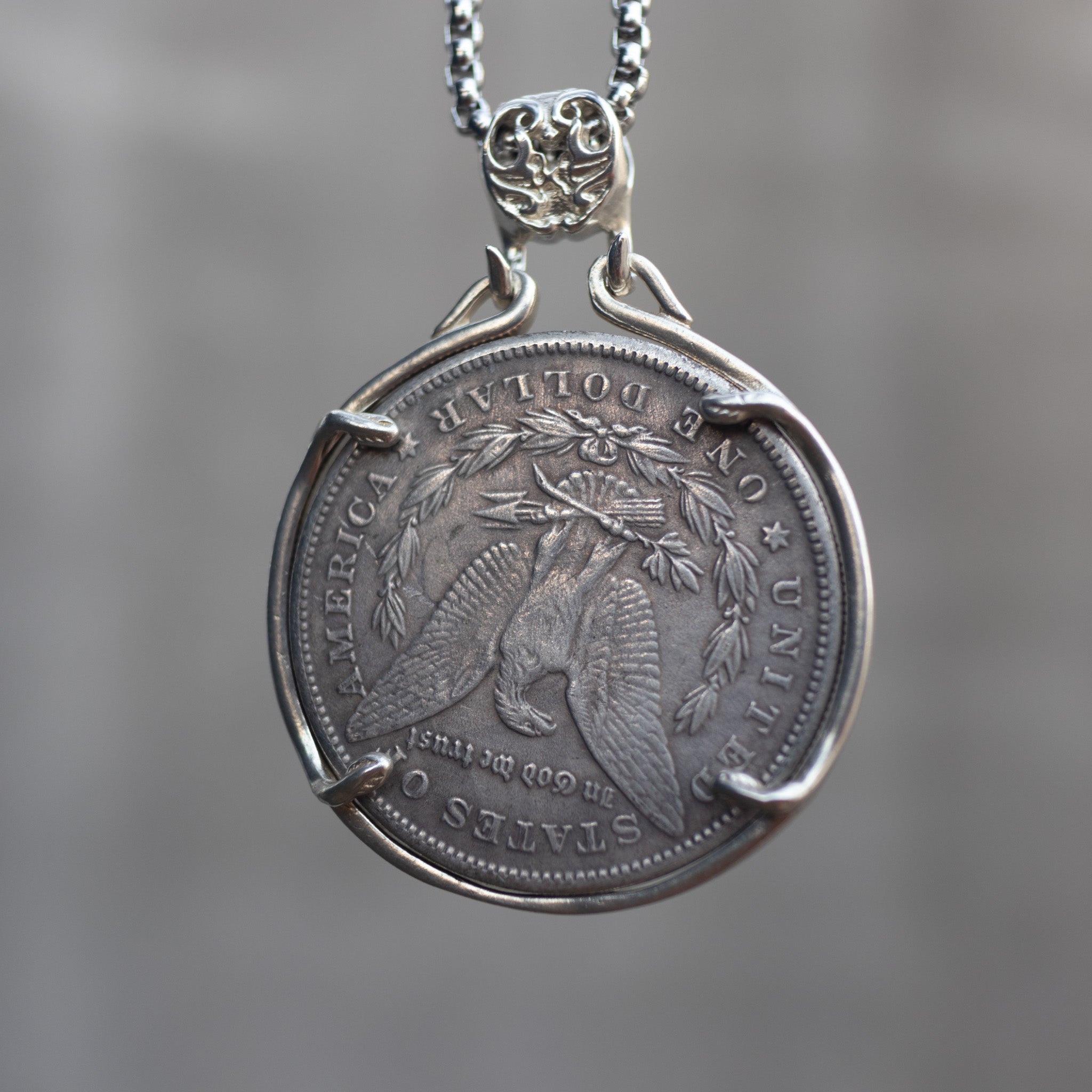 Morgan Dollar reverse showing the American eagle with spread wings, In God We Trust, United States of America, and One Dollar denomination on dark stone