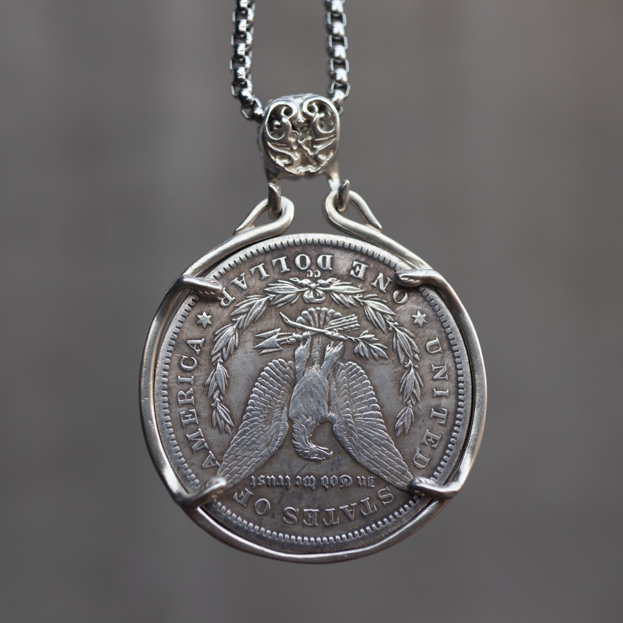 Danse Macabre skeleton couple coin pendant reversed to show the Morgan Dollar eagle with United States of America and One Dollar inscription, in a four-prong open bezel