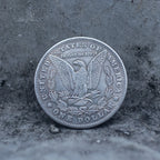 Morgan Dollar reverse showing the American eagle with spread wings, In God We Trust, United States of America, and One Dollar denomination on dark stone