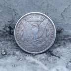 Morgan Dollar reverse showing the American eagle with spread wings, In God We Trust, United States of America, and One Dollar denomination on dark stone