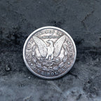 Morgan Dollar reverse showing the American eagle with spread wings, In God We Trust, United States of America, and One Dollar denomination on dark stone surface