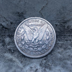 Morgan Dollar reverse showing the American eagle, In God We Trust and United States of America inscriptions, One Dollar denomination on dark stone