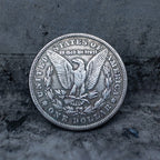 Morgan Dollar reverse showing the American eagle with spread wings, In God We Trust, United States of America, and One Dollar denomination on dark stone