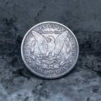 Morgan Dollar reverse showing the American eagle with spread wings, In God We Trust, United States of America, and One Dollar denomination on dark stone