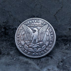 Morgan Dollar reverse with American eagle, In God We Trust and United States of America inscriptions, One Dollar denomination on dark stone surface