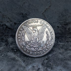 Morgan Dollar reverse with American eagle, In God We Trust and United States of America inscriptions, One Dollar denomination on dark stone