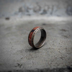 Norse rune wood inlay ring side view showing natural redwood inlay stripe and Elder Futhark rune border on oxidized stainless steel, Viking dark aesthetic ring by Veilhinge