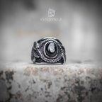 Coiled snake ring with oval obsidian stone centerpiece — silver serpent scales wrapping both sides, front view on stone surface