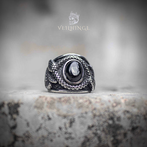 Coiled snake ring with oval obsidian stone centerpiece — silver serpent scales wrapping both sides, front view on stone surface