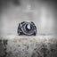 Coiled snake ring with oval obsidian stone centerpiece — silver serpent scales wrapping both sides, front view on stone surface