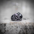 Side angle of coiled serpent ring showing textured snake scale engraving and obsidian cabochon set at center — oxidized silver finish