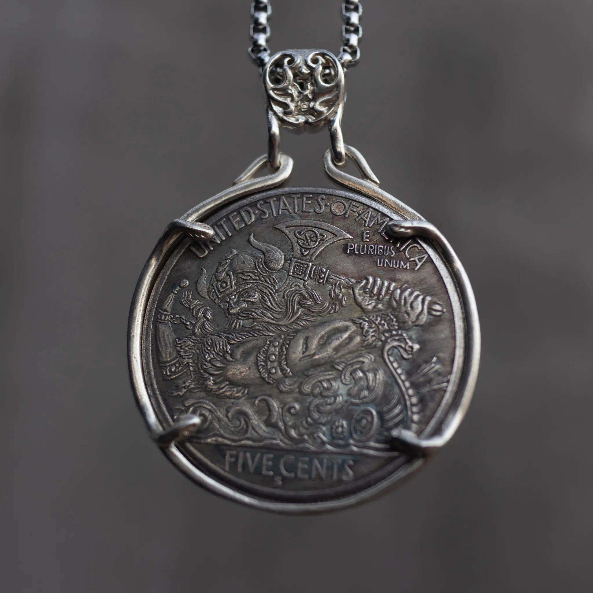 Viking Odin coin pendant set in a four-prong open bezel with ornate skull bail, obverse face forward on a box chain, dark stone background Main image