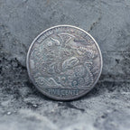 Hobo nickel coin engraved with Odin in a horned helmet wielding an axe aboard a dragon-prow Viking longship, Five Cents obverse face on stone background