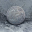 Hobo nickel coin engraved with Odin in a horned helmet wielding an axe aboard a dragon-prow Viking longship, Five Cents obverse face on stone background