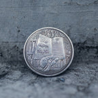 Close-up of the One More Chapter face of a coin engraved with a reader leaning against stacked books, open book and bookshelves in background