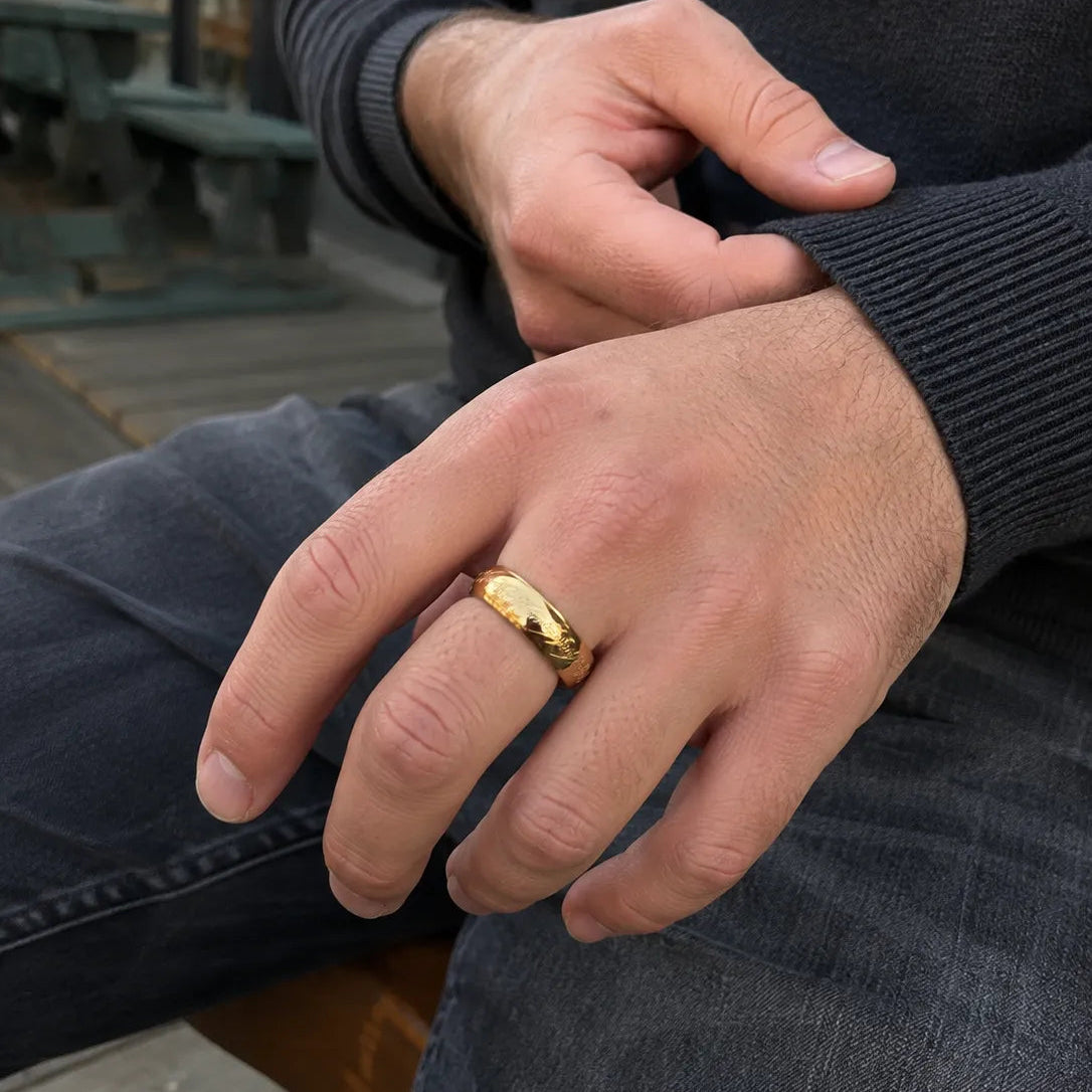Man wearing a mirror-polished gold-tone band with flowing fantasy-script engraving
