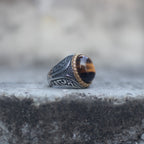 Side view of an oversized tiger eye ring with an ornate silver-tone band