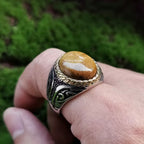 Side view of a large tiger eye signet ring worn on the finger